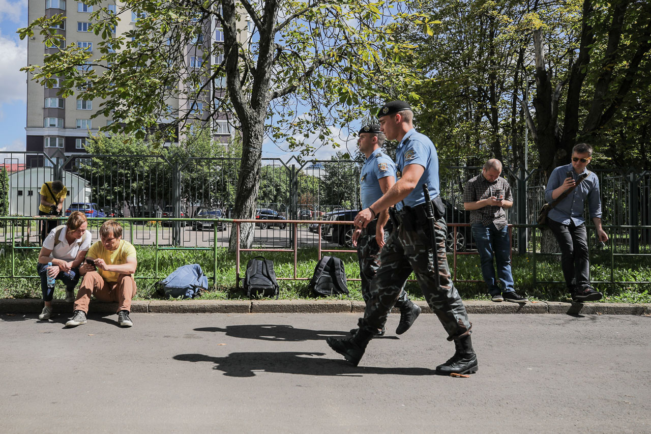 Супрацоўнікі АМАП праходзяць міма журналістаў БелаПАН, якіх не пускаюць у рэдакцыю падчас вобшуку